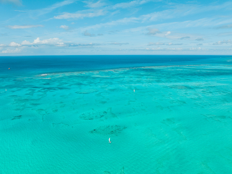 Aerial view of Grace Bay with turquoise waters coral reefs and small sailboats under a clear blue sky in Grace Bay Caicos Islands Turks and Caicos Islands. Aerial view of Grace Bay with turquoise waters coral reefs and small sailboats under a clear blue sky in Grace Bay Caicos Islands Turks and Caicos Islands.