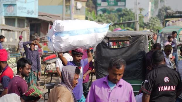 View of a man carrying a large sack on his head in Bogura Bangladesh. View of a man carrying a large sack on his head in Bogura Bangladesh.