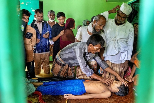Banshkhali Upazila Chittagong Division Bangladesh 10 July 2026 View of a man checking the pulse of a boy lying on a mat in a flooded room surrounded by concerned onlookers. Banshkhali Upazila Chittagong Division Bangladesh 10 July 2026 View of a man checking the pulse of a boy lying on a mat in a flooded room surrounded by concerned onlookers.