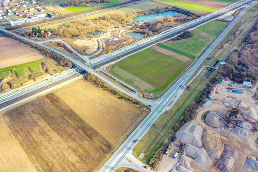 Aerial view of a highway bridge crossing a railway line surrounded by agricultural fields a small pond and a gravel quarry site in Forchheim Bavaria Germany. Aerial view of a highway bridge crossing a railway line surrounded by agricultural fields a small pond and a gravel quarry site in Forchheim Bavaria Germany.