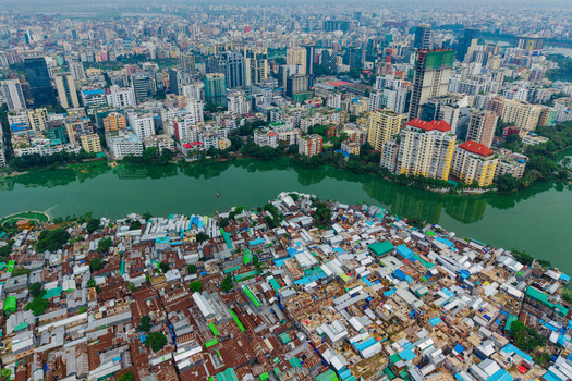 Dhaka Bangladesh 19 June 2026 Aerial view of Gulshan Lake showing the contrast between dense informal settlements with metal roofs and modern high rise buildings in the background.