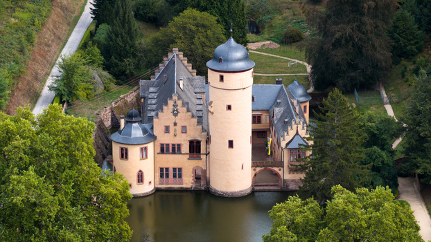 Aerial view of Schloss Mespelbrunn a historic water castle surrounded by lush green forests and a tranquil moat in Mespelbrunn Bayern Germany. Aerial view of Schloss Mespelbrunn a historic water castle surrounded by lush green forests and a tranquil moat in Mespelbrunn Bayern Germany.