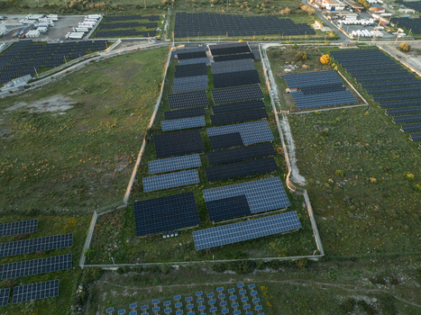 Aerial view of a large solar farm with rows of photovoltaic panels on green fields near an industrial zone in Augusta Sicily Italy. Aerial view of a large solar farm with rows of photovoltaic panels on green fields near an industrial zone in Augusta Sicily Italy.
