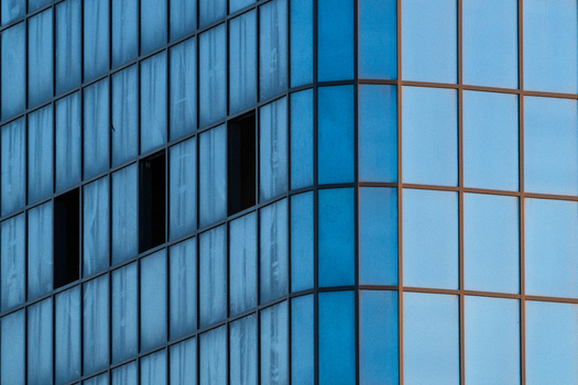 View of the modern glass facade of a building with reflective blue panels and dark window frames in Aktau Mangystau Region Kazakhstan.