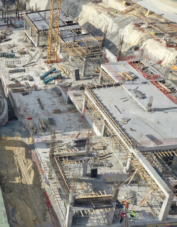 Aerial view of a large construction site with concrete foundations a yellow crane and workers in high visibility vests in Avcilar Istanbul Turkiye. Aerial view of a large construction site with concrete foundations a yellow crane and workers in high visibility vests in Avcilar Istanbul Turkiye.