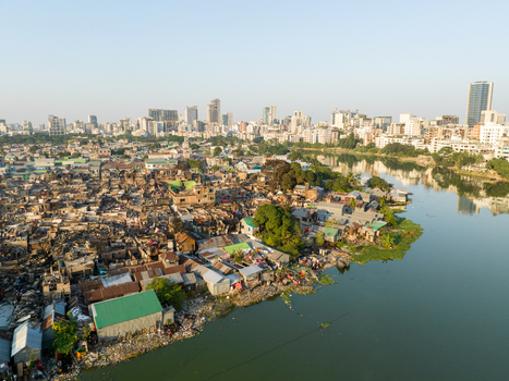 Aerial view of a sharp contrast between the dense haphazard settlements along the riverbank and the modern skyline in the distance Dhaka Dhaka Division Bangladesh. Aerial view of a sharp contrast between the dense haphazard settlements along the riverbank and the modern skyline in the distance Dhaka Dhaka Division Bangladesh.
