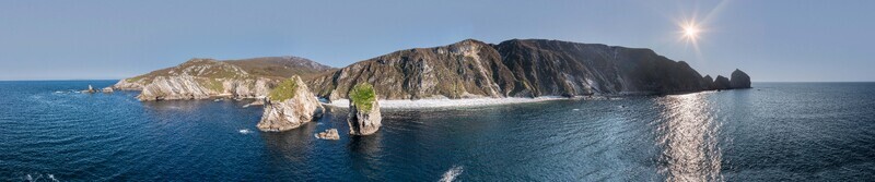 Aerial view of Glenlough Bay featuring dramatic sea cliffs rugged coastline and rocky sea stacks rising from the Atlantic Ocean near Ardara County Donegal Ireland.