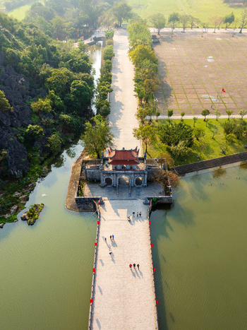 Aerial view of the historic gate and stone bridge at Hoa Lu Ancient Capital surrounded by lush greenery and water in Vietnam. Aerial view of the historic gate and stone bridge at Hoa Lu Ancient Capital surrounded by lush greenery and water in Vietnam.