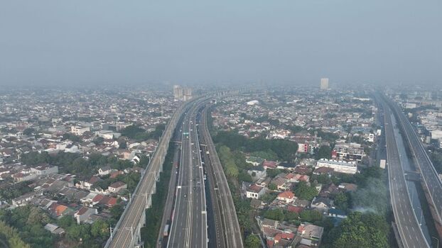 Aerial view of the Jakarta Cikampek elevated toll road winding through the dense urban landscape with residential areas and lush greenery in Bekasi Barat West Java Indonesia. Aerial view of the Jakarta Cikampek elevated toll road winding through the dense urban landscape with residential areas and lush greenery in Bekasi Barat West Java Indonesia.