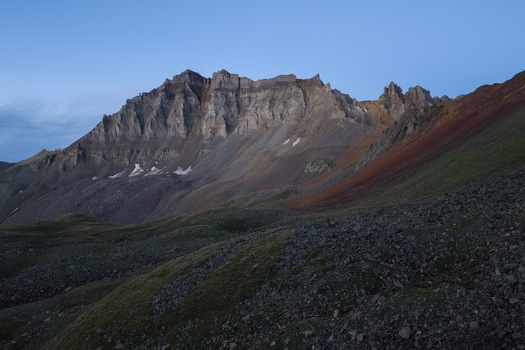 Aerial view of the rugged Gilpin Peak in Yankee Boy Basin with rocky slopes and alpine terrain under a clear blue sky in Ouray Colorado United States.