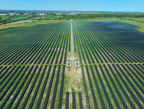 Aerial view of a large solar farm with rows of photovoltaic panels in green fields under a clear blue sky in Little Irchester England United Kingdom. Aerial view of a large solar farm with rows of photovoltaic panels in green fields under a clear blue sky in Little Irchester England United Kingdom.