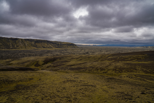 View of a vast rugged landscape with moss covered lava fields stretching under a dramatic brooding sky Skaftárhreppur Iceland. View of a vast rugged landscape with moss covered lava fields stretching under a dramatic brooding sky Skaftárhreppur Iceland.