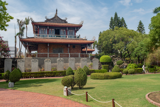 View of Chihkan Tower featuring traditional architecture with a tiled roof and brick walls set in a garden with trimmed hedges and a brick pathway in Chihkan Village Tainan City Taiwan. View of Chihkan Tower featuring traditional architecture with a tiled roof and brick walls set in a garden with trimmed hedges and a brick pathway in Chihkan Village Tainan City Taiwan.