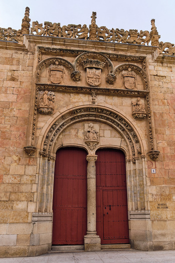 Salamanca Spain 29 November 2025 View of the ornate Plateresque entrance of the University of Salamanca featuring intricate stone carvings coats of arms and red double doors.