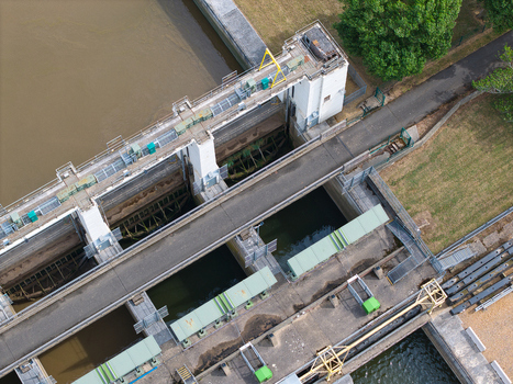 Aerial view of the Tail Sluice water control structure featuring concrete walls metal gates and a service bridge over the river King s Lynn England United Kingdom.