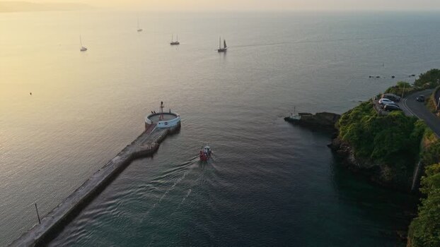 Aerial view of a boat entering Looe harbor at sunset United Kingdom. Aerial view of a boat entering Looe harbor at sunset United Kingdom.