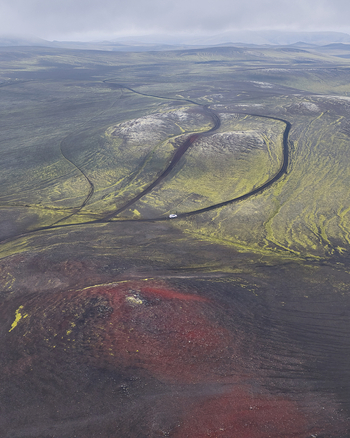 Aerial view of the volcanic Raudaskal crater surrounded by moss covered lava fields and a winding gravel road in the Icelandic highlands Rangarthing ytra Iceland. Aerial view of the volcanic Raudaskal crater surrounded by moss covered lava fields and a winding gravel road in the Icelandic highlands Rangarthing ytra Iceland.