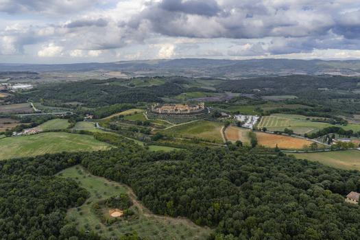 Aerial view of the historic walled town of Monteriggioni surrounded by lush green forests rolling hills and vineyards in the Tuscan countryside Monteriggioni Tuscany Italy.