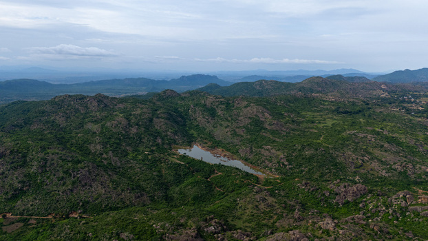 Aerial view of lush green hills and a serene lake nestled amongst the peaks under a soft sky Hosur Tamil Nadu India.