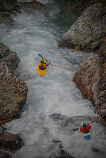 View of kayakers navigating the white water rapids of the Rio Manso through a narrow rocky canyon in San Carlos de Bariloche Rio Negro Argentina. View of kayakers navigating the white water rapids of the Rio Manso through a narrow rocky canyon in San Carlos de Bariloche Rio Negro Argentina.