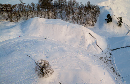 Aerial view of the snow covered Kernave hillforts with bare trees and winding paths under soft winter light Kernave Vilnius County Lithuania.