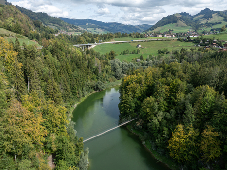 Aerial view of Lac de Montsalvens surrounded by dense forests rolling hills and a suspension bridge crossing the calm water in Gruyere District Fribourg Switzerland. Aerial view of Lac de Montsalvens surrounded by dense forests rolling hills and a suspension bridge crossing the calm water in Gruyere District Fribourg Switzerland.