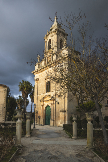 View of the historic Baroque church of San Giacomo Apostolo with its ornate bell tower and green door under a dramatic sky in Ragusa Sicily Italy.