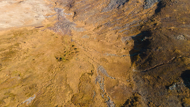 Aerial view of Deosai Plains featuring vast golden grasslands winding streams and rocky terrain in Skardu Gilgit Pakistan.