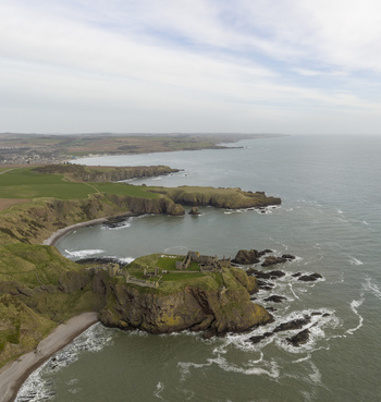 Aerial view of Dunnottar Castle ruins on a rocky cliff edge overlooking the North Sea with green fields Stonehaven Scotland United Kingdom. Aerial view of Dunnottar Castle ruins on a rocky cliff edge overlooking the North Sea with green fields Stonehaven Scotland United Kingdom.