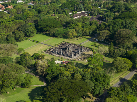 Aerial view of Lumbung Temple complex surrounded by lush green trees and manicured lawns in Kecamatan Prambanan Daerah Istimewa Yogya Indonesia.