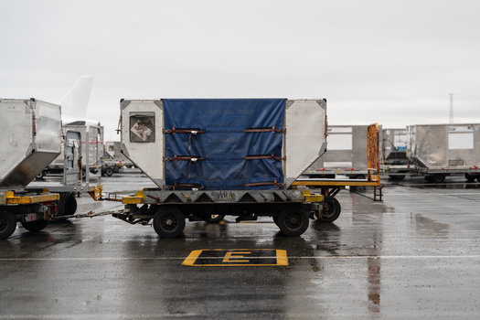 View of cargo containers on dollies at an airport tarmac in Iceland. View of cargo containers on dollies at an airport tarmac in Iceland.