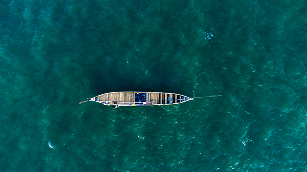 Aerial view of a traditional wooden fishing boat floating on the turquoise waters of the Atlantic Ocean in Prampram Greater Accra Region Ghana.