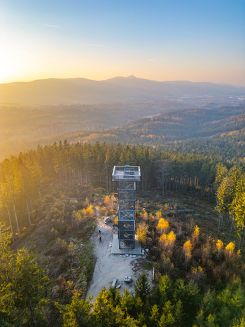 Aerial view of Cisaruv kamen lookout tower surrounded by autumn forest and hills during golden hour in Liberec 30 Liberec Region Czechia. Aerial view of Cisaruv kamen lookout tower surrounded by autumn forest and hills during golden hour in Liberec 30 Liberec Region Czechia.
