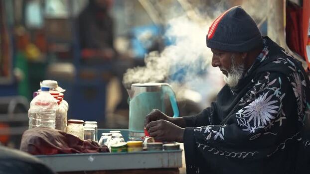 View of an elderly man preparing tea at a street stall Bangladesh.
