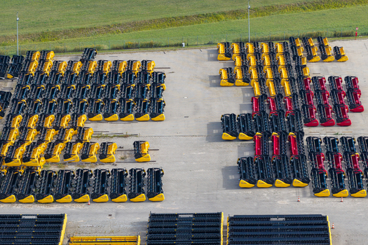 Plock Poland 10 September 2026 Aerial view of rows of yellow and red combine harvester headers stored in an industrial yard at a harvesting machinery manufacturing facility. Plock Poland 10 September 2026 Aerial view of rows of yellow and red combine harvester headers stored in an industrial yard at a harvesting machinery manufacturing facility.