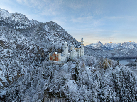 Aerial view of Neuschwanstein Castle rises majestically amidst a snowy landscape its fairy tale silhouette contrasting against the alpine backdrop Schwangau Bayern Germany.