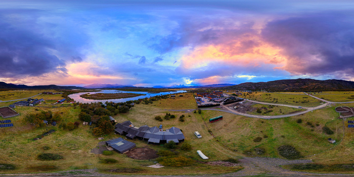 Aerial view of Rio Serrano Hotel Spa near the winding Serrano River under a dramatic sunset sky in Torres del Paine Magallanes Chile.