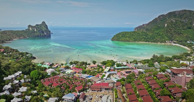 Aerial view of the coastal landscape in Phuket featuring turquoise waters coral reefs lush green hills and resort buildings with red roofs in Phuket Phuket Thailand. Aerial view of the coastal landscape in Phuket featuring turquoise waters coral reefs lush green hills and resort buildings with red roofs in Phuket Phuket Thailand.