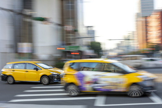 View of yellow taxis driving through a city intersection with motion blur and urban buildings in Taipei City Taiwan. View of yellow taxis driving through a city intersection with motion blur and urban buildings in Taipei City Taiwan.