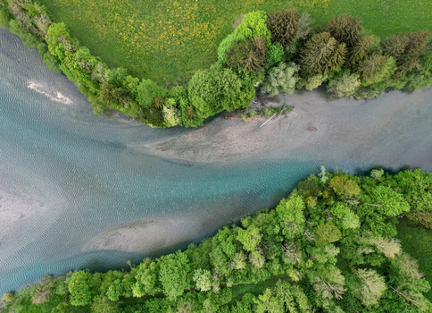 Aerial view of the turquoise waters and sandy banks of Lac du Vernex surrounded by lush green forest in Rossiniere Vaud Switzerland.