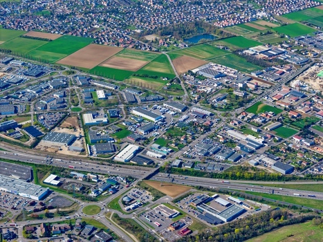 Aerial view of the sprawling urban landscape meeting patchwork fields under a vast sky showcasing the blend of industry and agriculture Sausheim Grand Est France.