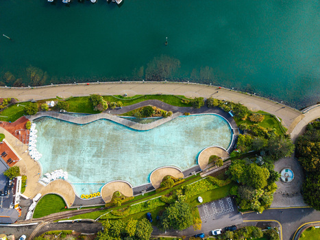 Aerial view of the outdoor swimming pool and surrounding parkland at Bangor Harbour featuring turquoise water paved walkways and lush green gardens in Bangor Northern Ireland United Kingdom.