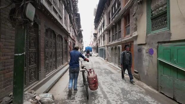 View of a man pushing a bicycle in a narrow street Nepal. View of a man pushing a bicycle in a narrow street Nepal.