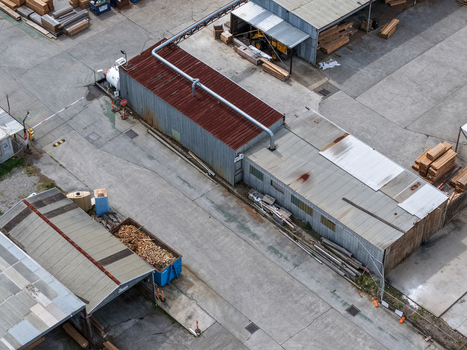 Melbourne VIC Australia 25 September 2026 Aerial view of industrial wood processing facility with metal sheds stacks of timber and machinery in a concrete yard.