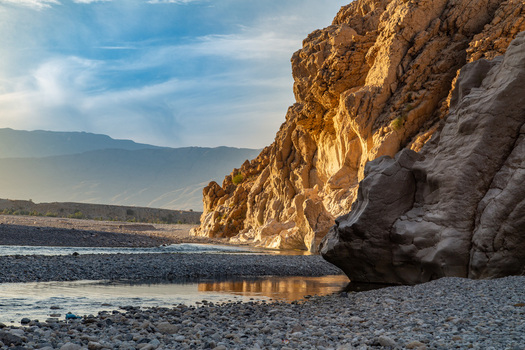 Aerial view of the sun kissed cliffs casting long shadows over the rocky riverbed contrasting with the cool blue waters Pakistan. Aerial view of the sun kissed cliffs casting long shadows over the rocky riverbed contrasting with the cool blue waters Pakistan.