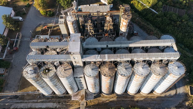 Aerial view of a large industrial grain silo complex with multiple cylindrical storage tanks and metal roofs surrounded by greenery in Sremska Mitrovica Vojvodina Serbia. Aerial view of a large industrial grain silo complex with multiple cylindrical storage tanks and metal roofs surrounded by greenery in Sremska Mitrovica Vojvodina Serbia.