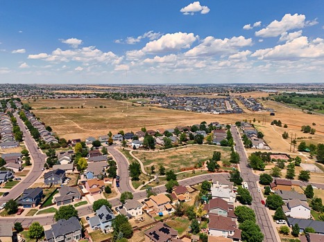 Aerial view of residential neighborhoods with suburban houses winding streets and open fields under a blue sky in Thornton Colorado United States. Aerial view of residential neighborhoods with suburban houses winding streets and open fields under a blue sky in Thornton Colorado United States.