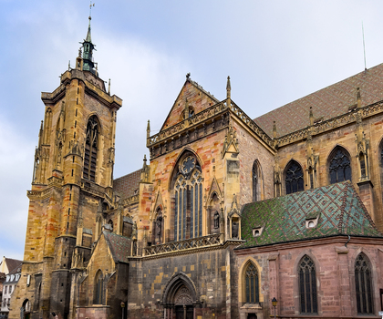View of the Collegiate Church of Saint Martin featuring its tall bell tower intricate Gothic stone facade and colorful tiled roof in Colmar Grand Est France.