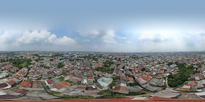 Aerial view of the urban landscape of Depok featuring dense residential rooftops lush green trees and a mosque dome under a clear blue sky in Depok West Java Indonesia. Aerial view of the urban landscape of Depok featuring dense residential rooftops lush green trees and a mosque dome under a clear blue sky in Depok West Java Indonesia.
