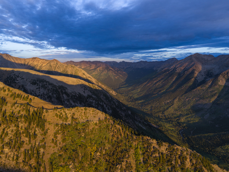 Aerial view of Missouri Mountain and the rugged Missouri Gulch Trail at sunrise with golden light on the peaks and deep shadows in the valley in Buena Vista Colorado United States.